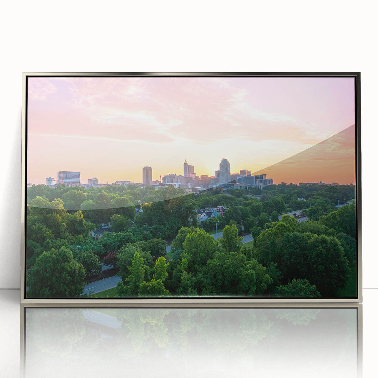 Mid-century modernist art depicting Raleigh skyline in muted gray and blue tones on a silver-framed acrylic print.
