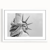 Abstract art print of the Statue of Liberty with vibrant blue and green hues on a white framed mat.