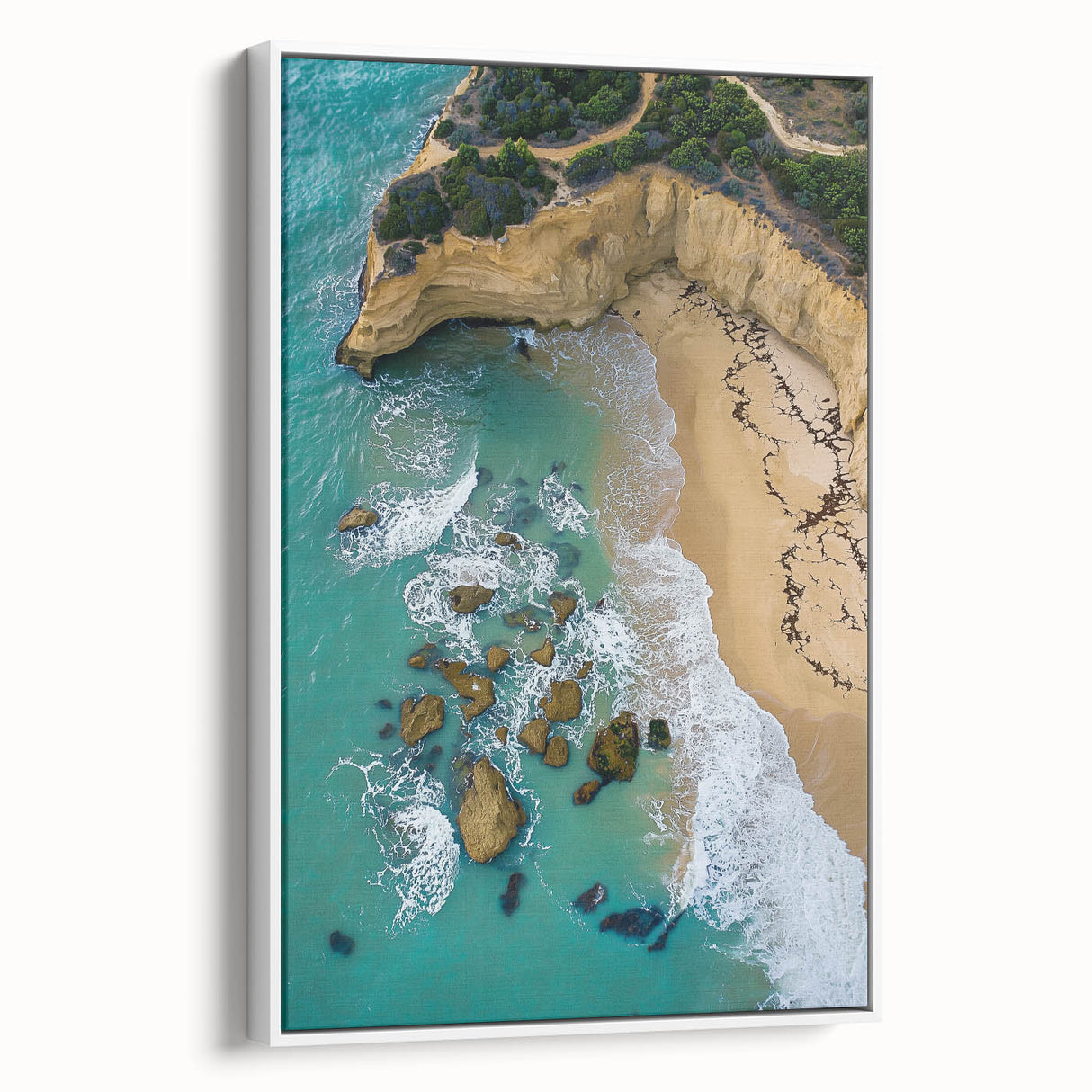 Framed canvas artwork depicting a dramatic landscape with towering cliffs and lush greenery, presented in a sleek white frame, ideal for modern home decor.