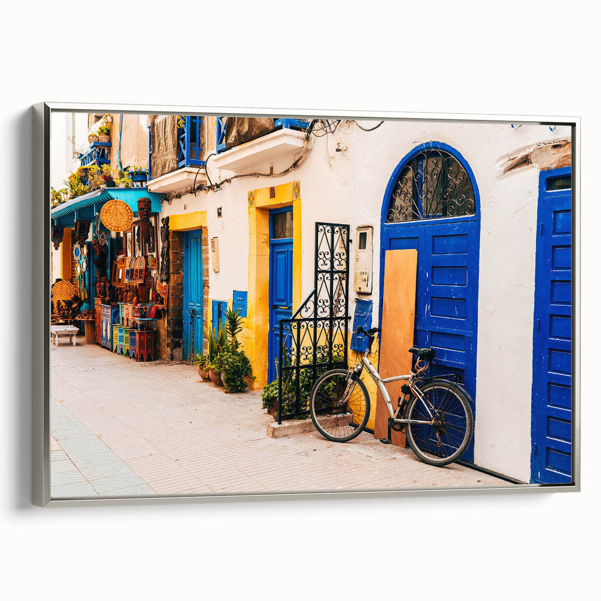 Vintage poster art of a Moroccan landscape in colorful hues on a silver-framed canvas.