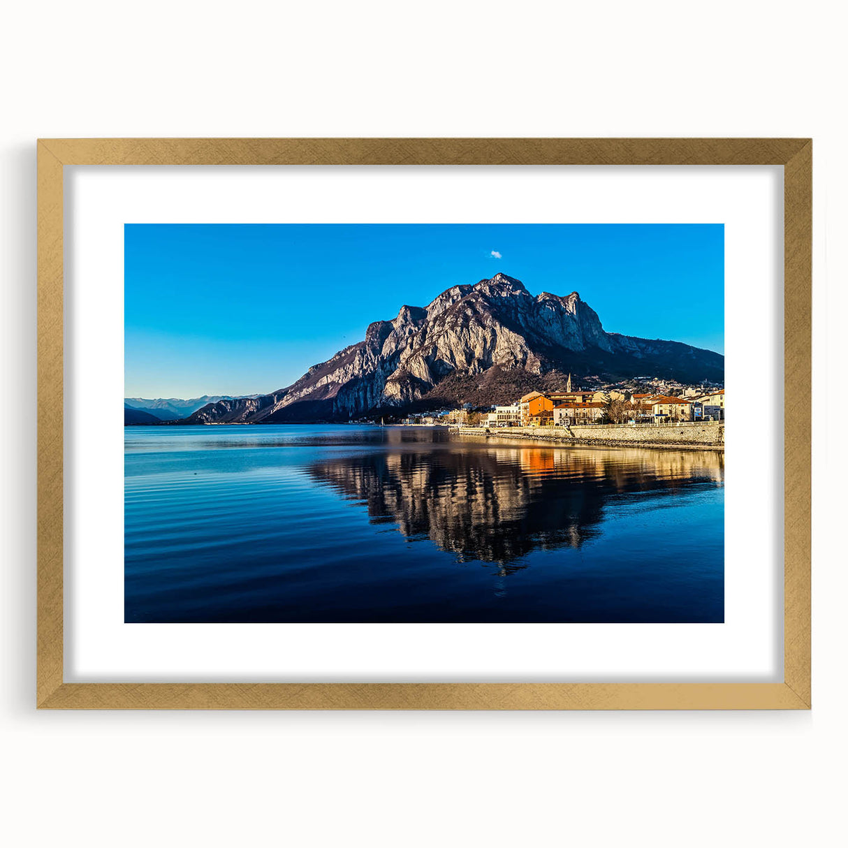 Abstract art print of Lake Como with muted blue and green hues on a framed gold mat, ideal for dining room decor.