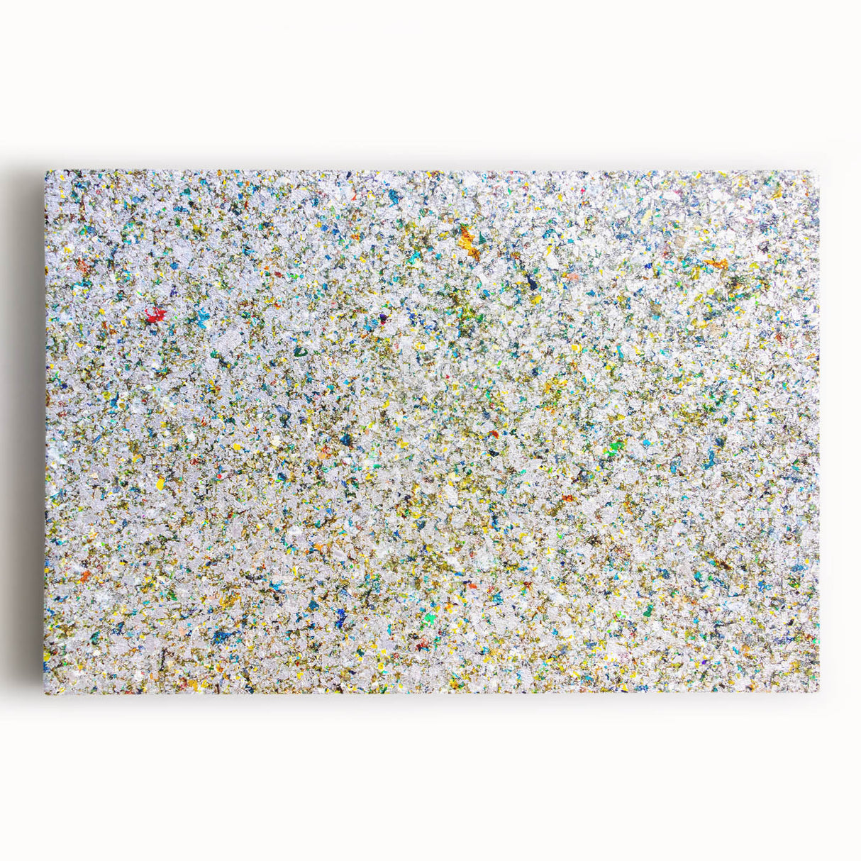Abstract splatter art on a stretched canvas, showcasing vibrant colors of blue, yellow, and red, perfect for modern home decor and artistic expression.