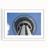 Abstract art print of Auckland skyline in muted blue and grey tones, framed with a white mat, ideal for dining room decor.