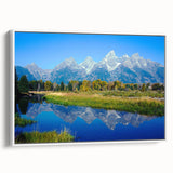 Vintage poster art of the Grand Tetons with vibrant green and blue tones on a framed canvas.