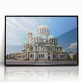 Large abstract wall art depicting a European scenery in muted earth tones on a black framed acrylic print.