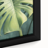 Close-up of a framed canvas wall art featuring vibrant floral and botanical designs with lush green leaves, perfect for home decor and adding a natural aesthetic.