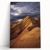 Stretched canvas artwork depicting a vibrant desert landscape with warm hues of orange and yellow, leaning against a neutral wall, perfect for home decor.