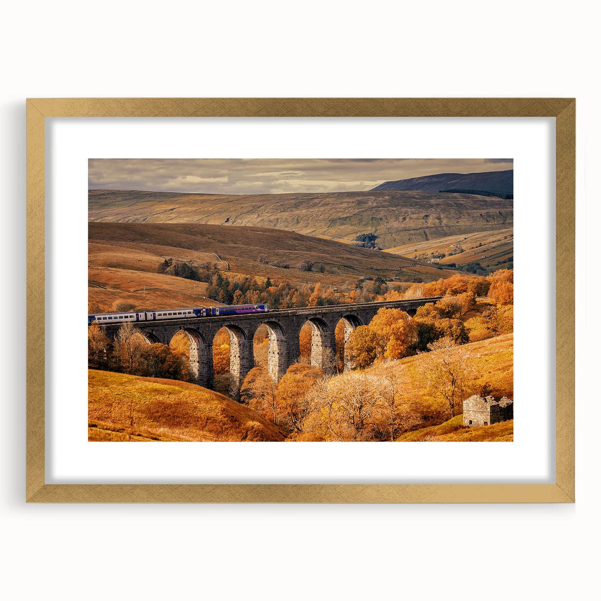 Abstract art print of Cumbria's landscape in muted earth tones on a gold-framed canvas, suitable for dining room decor.