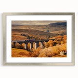 Extra large abstract art print depicting a textured European scenery in muted earth tones, framed in silver.