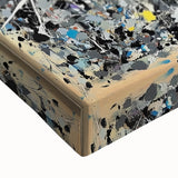 Close-up view of an abstract art canvas featuring vibrant splatter patterns in shades of blue, yellow, and red, ideal for modern home decor or gallery displays.