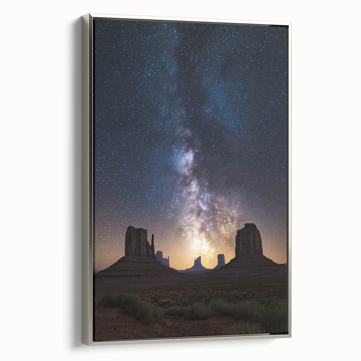 Framed canvas artwork showcasing a desert landscape with vibrant hues of orange and red, elegantly displayed with a sleek silver frame, perfect for modern decor.