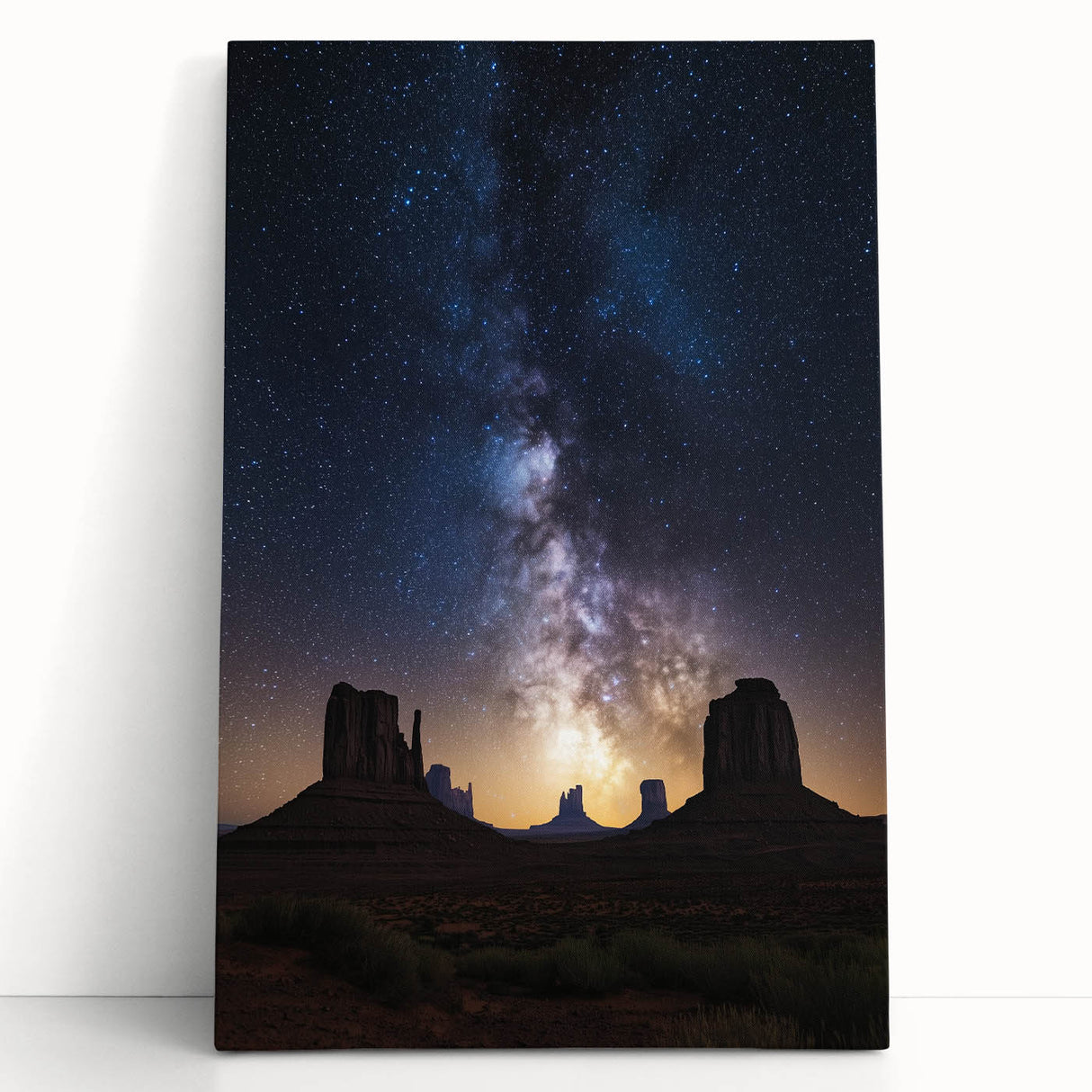 Stretched canvas artwork depicting a vibrant desert landscape with warm hues of orange and yellow, leaning against a neutral wall, enhancing modern decor aesthetics.