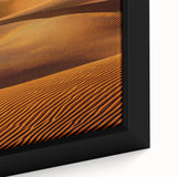 Close-up of a framed canvas artwork showcasing serene sand dunes at sunset, highlighting warm golden hues and intricate textures, perfect for home decor.