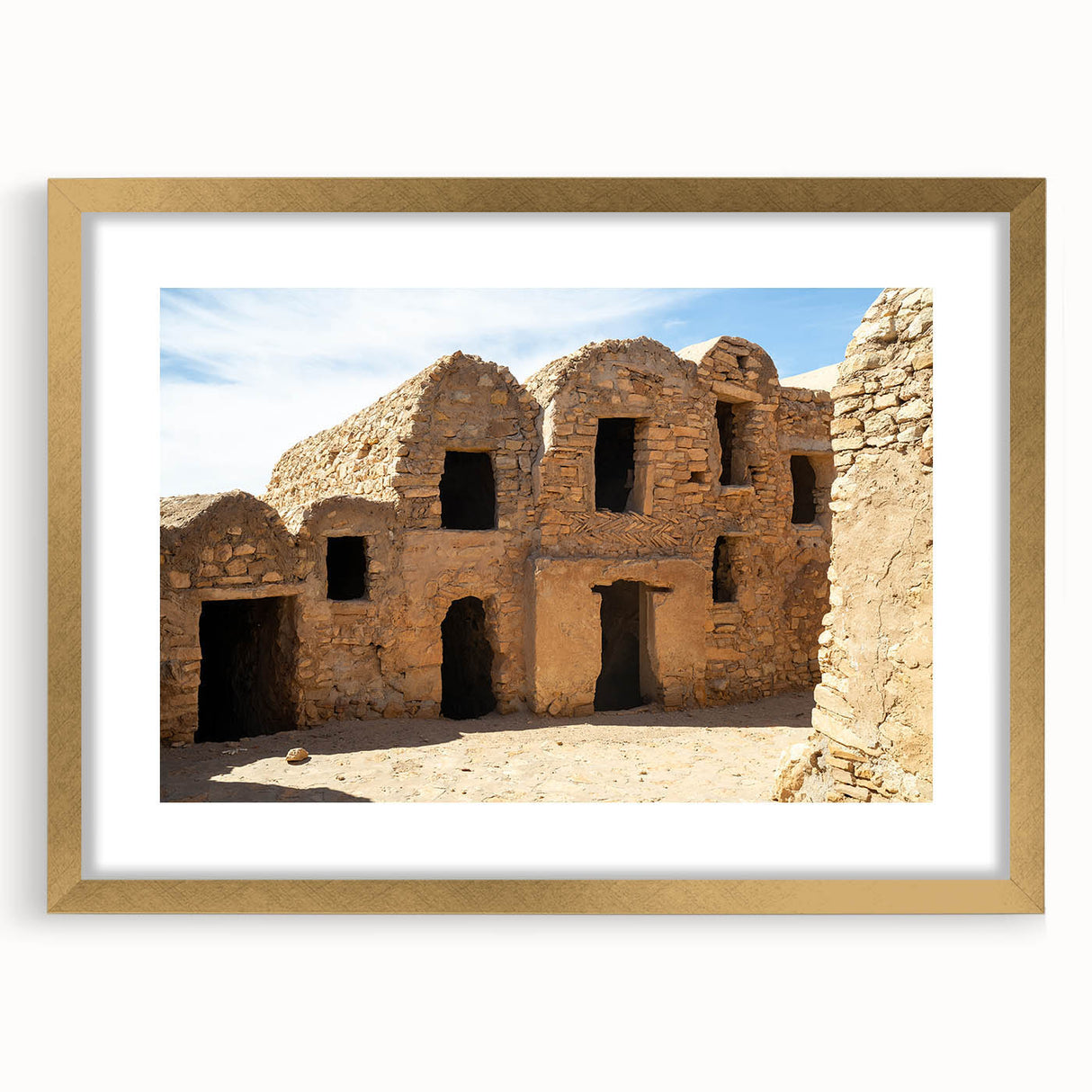 Extra large abstract art print depicting Moroccan scenery in textured gold tones, framed with a mat.