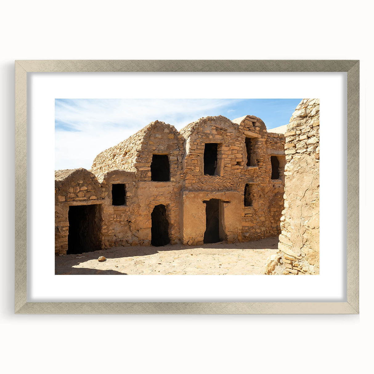 Textured abstract art print depicting a Moroccan landscape in earth tones, framed in silver, ideal for bedroom art.