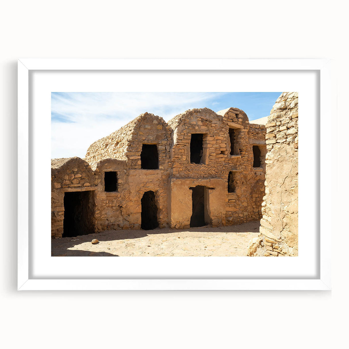 Abstract art print of a Moroccan landscape in earthy tones on a white-framed canvas, suitable for dining room decor.