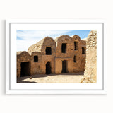 Abstract art print of a Moroccan landscape in earthy tones on a white-framed canvas, suitable for dining room decor.