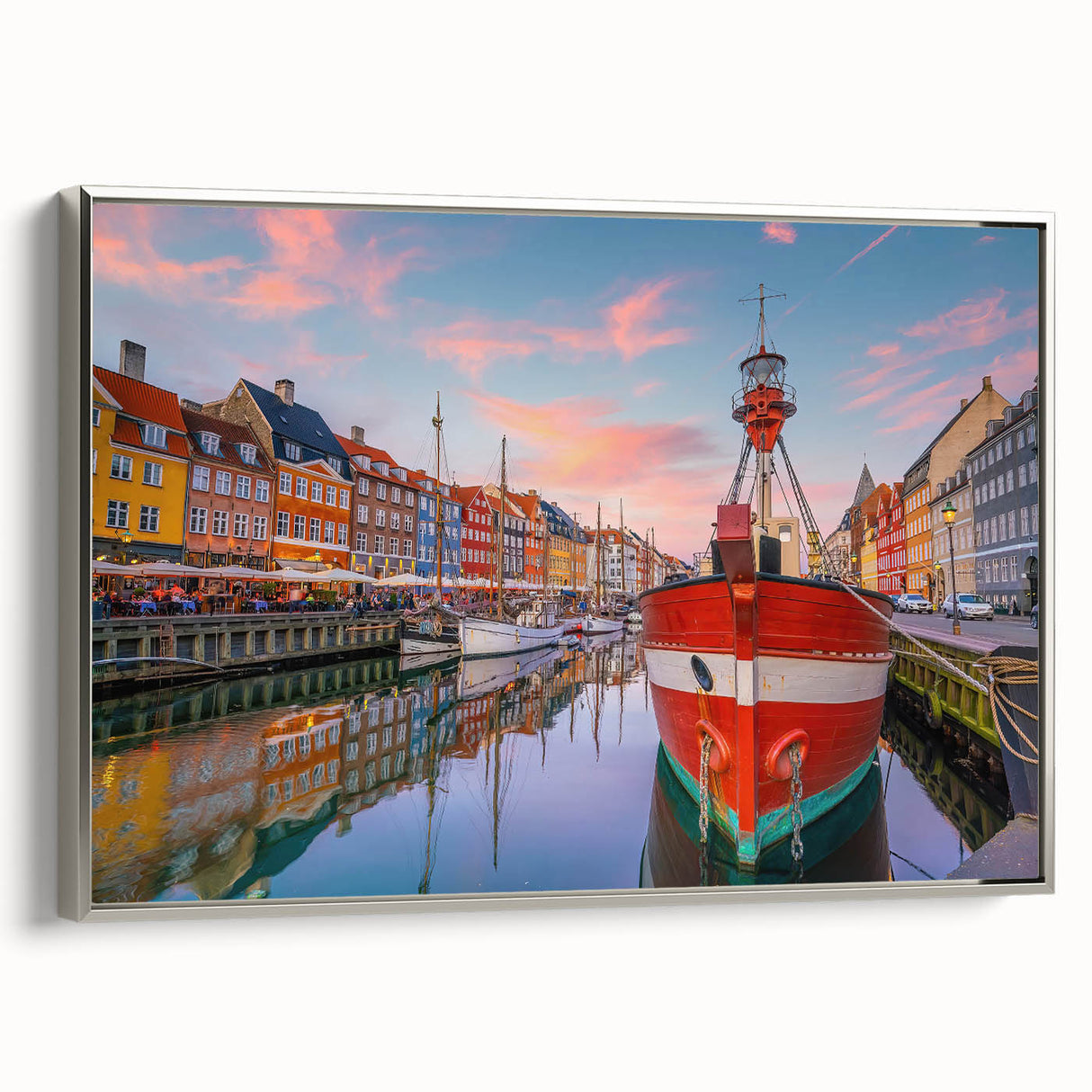 Framed canvas featuring a vintage poster art style landscape of a European town with colorful buildings and a black border.