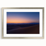 Framed desert landscape artwork with a silver mat, showcasing vibrant hues of orange and blue, perfect for adding a touch of nature to home decor.