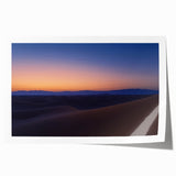Desert landscape rolled canvas print showcasing vibrant shades of orange and yellow, featuring abstract mountains under a blue sky, packaged securely in a cardboard tube.
