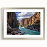 Framed landscape artwork depicting dramatic cliffs under a clear blue sky, featuring a sleek silver frame with a white mat, ideal for home decor.