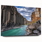 Acrylic landscape artwork showcasing dramatic cliffs and vibrant colors, displayed in a sleek glass frame from a side view, enhancing modern decor aesthetics.