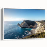Framed canvas artwork depicting a serene landscape with dramatic cliffs and gentle waves, featuring a white frame that enhances the vibrant colors.