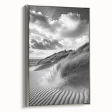 Framed canvas artwork depicting serene sand dunes under a blue sky, showcasing a silver frame that enhances the landscape's tranquil beauty. Perfect for modern home decor.
