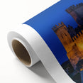 Rolled canvas artwork depicting a scenic landscape with a majestic castle, featuring vibrant colors and intricate details, elegantly packaged for display or gifting.