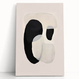 Abstract minimalist wall art featuring bold black and white geometric shapes on a stretched canvas, leaning against a neutral wall, perfect for modern decor.