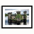 Framed landscape artwork showcasing a picturesque castle scene, featuring a black frame and matting that highlights the vibrant colors of the landscape, ideal for home decor.