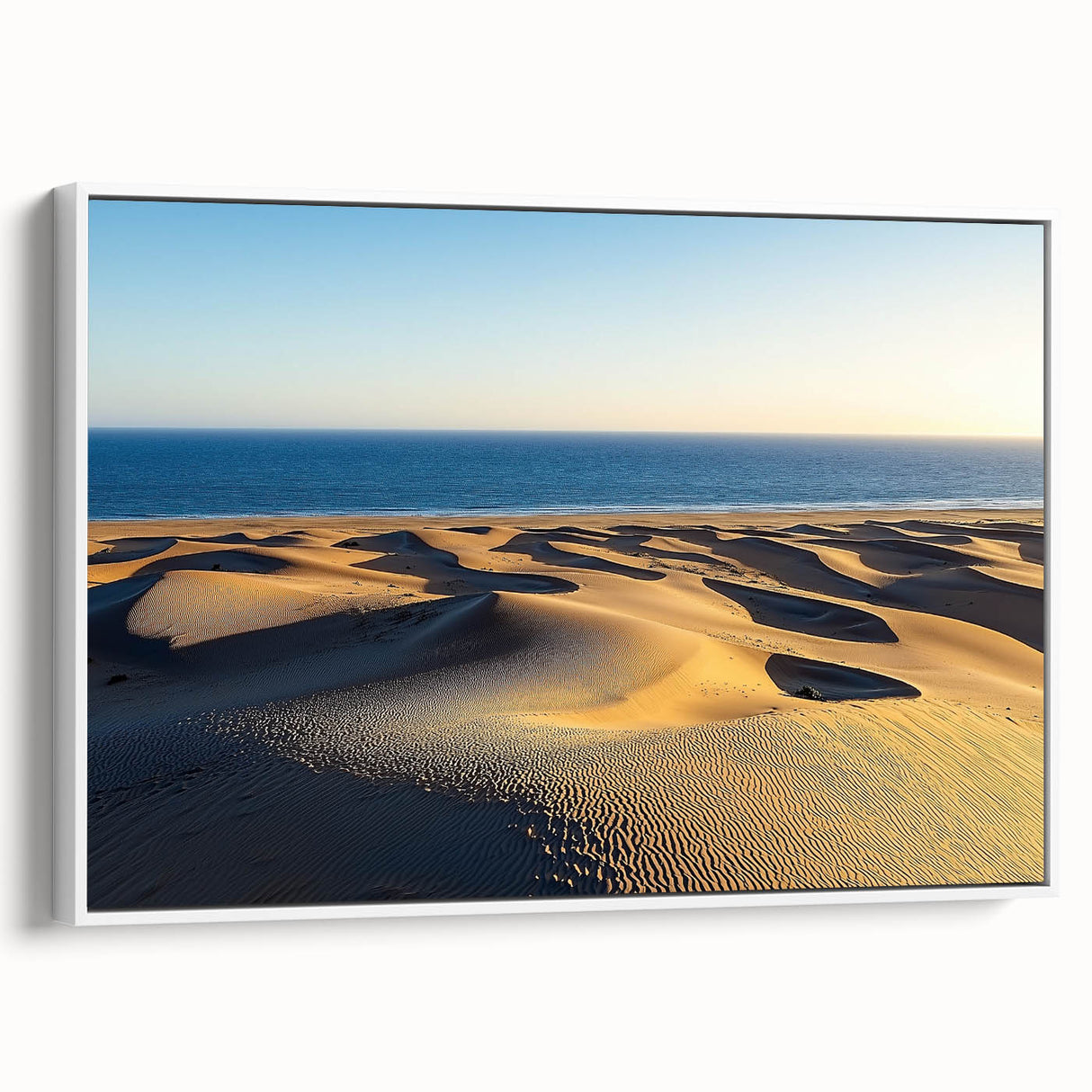 Framed canvas artwork showcasing serene desert dunes in soft beige and golden hues, set against a minimalist white frame, perfect for modern home decor.