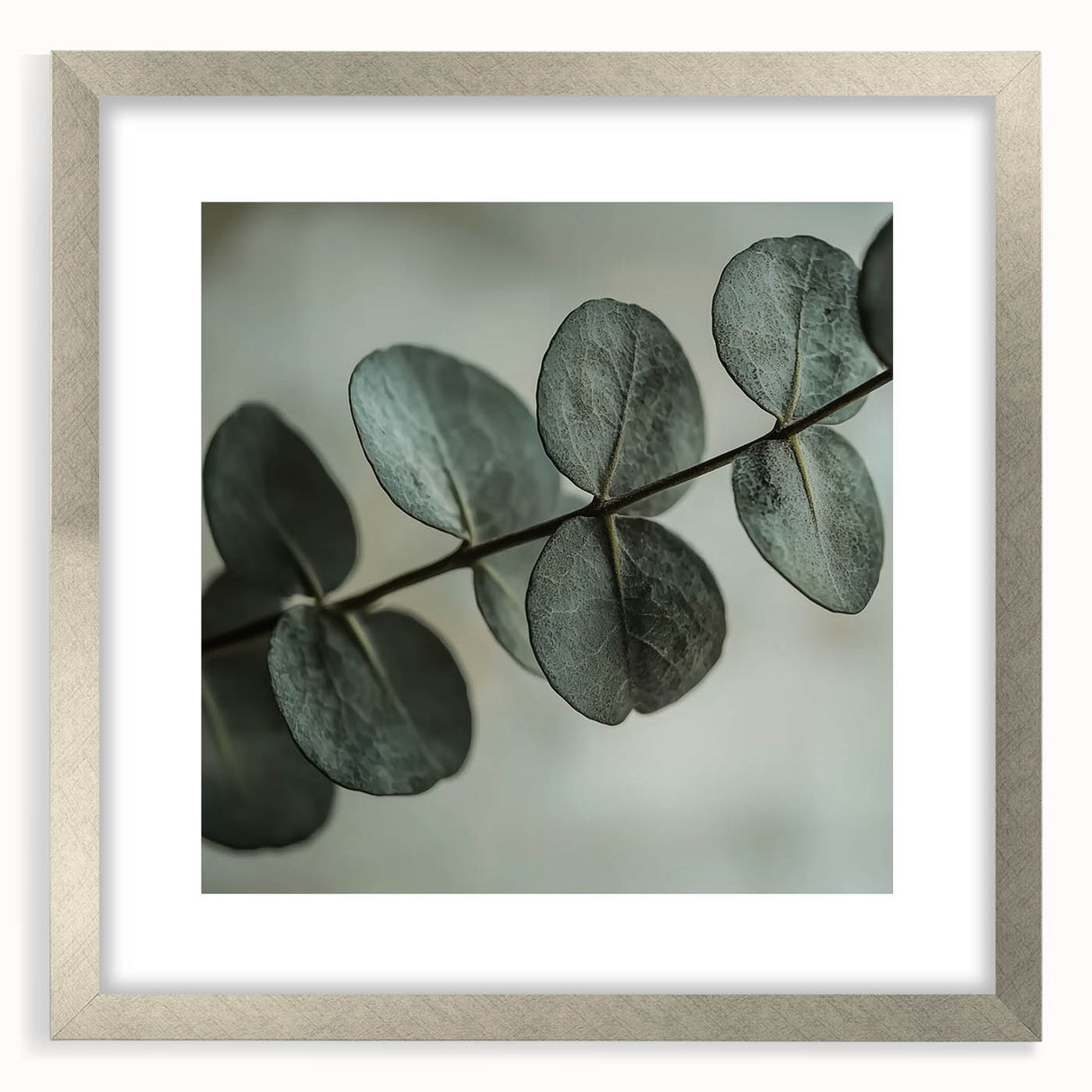 Textured art of abstract leaves in muted green and silver tones, framed with a silver mat, suitable for bedroom decor.