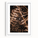 Abstract art print of autumn leaves in orange and brown tones on a white framed canvas.