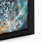 Close-up view of a framed abstract canvas art piece featuring vibrant splatter designs in shades of blue, yellow, and red, perfect for modern home decor.