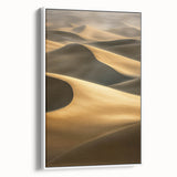 Framed canvas artwork showcasing a stunning desert landscape with golden dunes under a blue sky, elegantly displayed in a white frame, perfect for home decor.