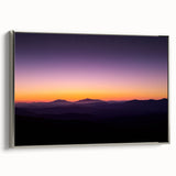 Framed canvas artwork depicting a stunning desert landscape with soft hues of orange and purple, showcased from a silver side view, ideal for home decor.