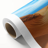 Rolled canvas depicting a serene desert landscape with rolling dunes under a vibrant sunset, showcasing warm hues and intricate textures, perfect for home decor.