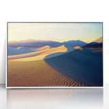 Framed acrylic artwork showcasing a serene landscape of golden sand dunes under a bright blue sky, elegantly displayed in a sleek white frame, perfect for modern decor.
