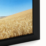 Close-up of a framed canvas depicting a serene countryside landscape with vibrant green fields and a clear blue sky, perfect for home decor.