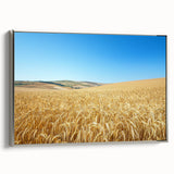 Framed canvas artwork depicting a serene countryside landscape with rolling hills and a clear blue sky, featuring a silver frame that enhances its elegance. Perfect for home decor.