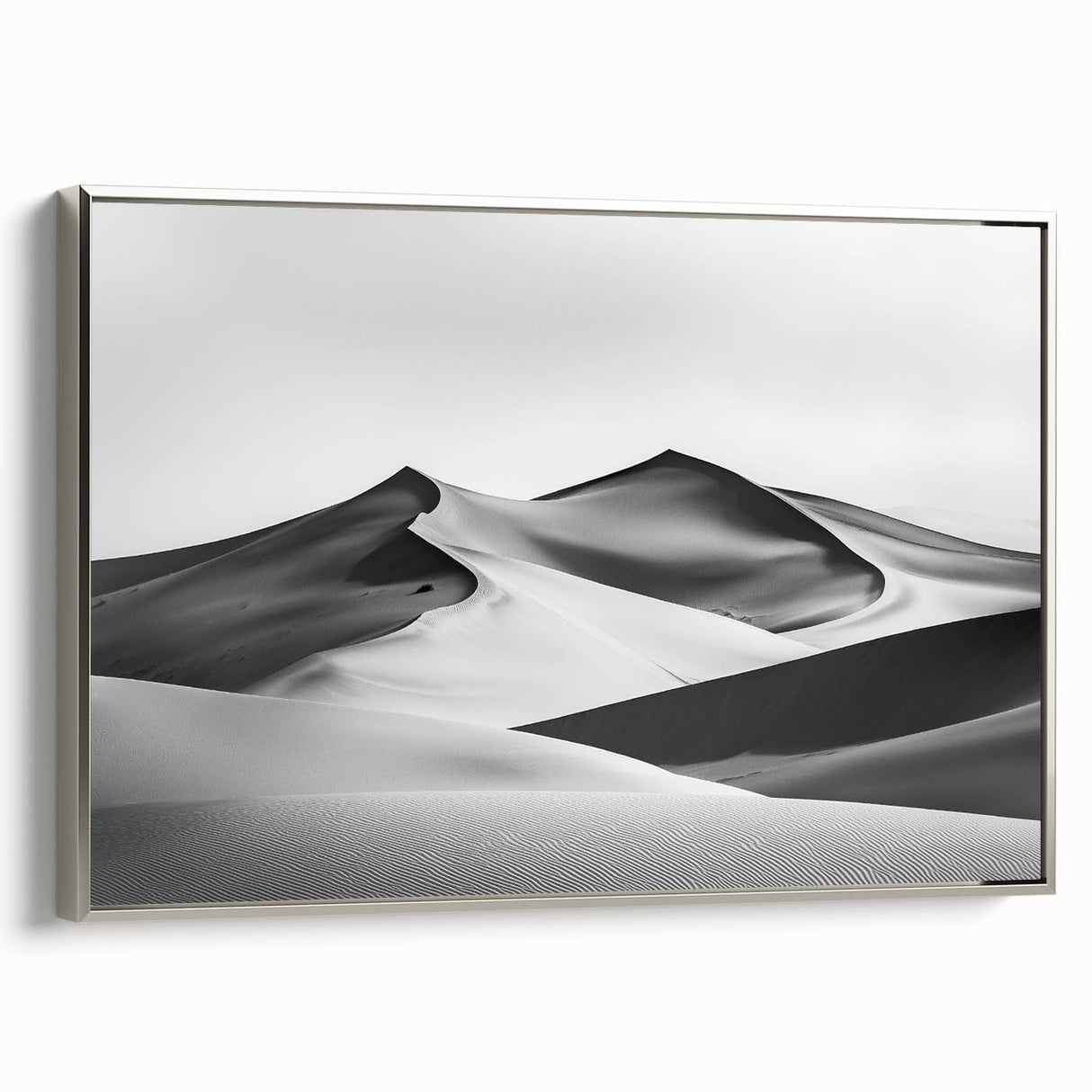 Framed canvas artwork depicting serene sand dunes under a soft sunset glow, featuring a silver frame. Perfect for enhancing modern home decor with a touch of nature.