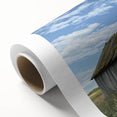 Landscape canvas art showcasing a serene barn scene with lush green fields and a vibrant blue sky, carefully rolled and secured in a protective tube for shipping.