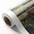Rolled canvas artwork showcasing a serene countryside landscape with vibrant green fields and a clear blue sky, elegantly packaged in a protective cardboard tube.