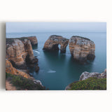 Stretched canvas artwork depicting a dramatic landscape with towering cliffs against a vibrant sunset sky, perfect for home decor or art enthusiasts.