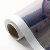 Rolled canvas artwork showcasing a serene landscape scene with a rustic barn, featuring rich colors and detailed textures, securely packaged in a protective tube.