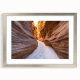 Framed landscape artwork depicting vibrant canyons in rich earth tones, set in a sleek silver frame with a mat, ideal for home decor or office spaces.