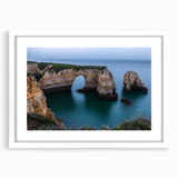 Framed landscape artwork showcasing dramatic cliffs under a vibrant sunset, featuring a white mat and sleek black frame, perfect for home decor enhancement.