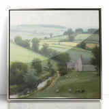 Framed landscape wall art depicting a serene countryside scene, featuring vibrant green fields and a clear blue sky, complemented by a sleek silver frame.
