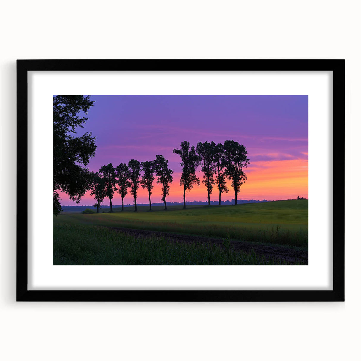 Black-framed landscape artwork showcasing a serene countryside scene with vibrant greenery and a clear blue sky, elegantly matted for a polished look.